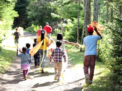 a group of people carrying kites while walking down a trail.