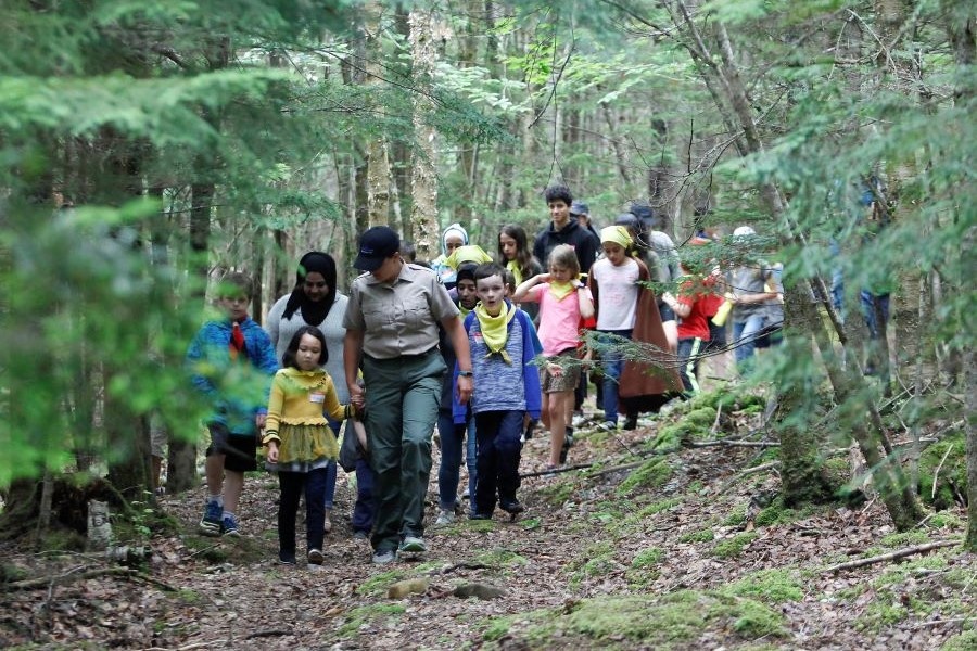 A DNRR staff member leads a group of children and youth on a nature walk in the forest.
