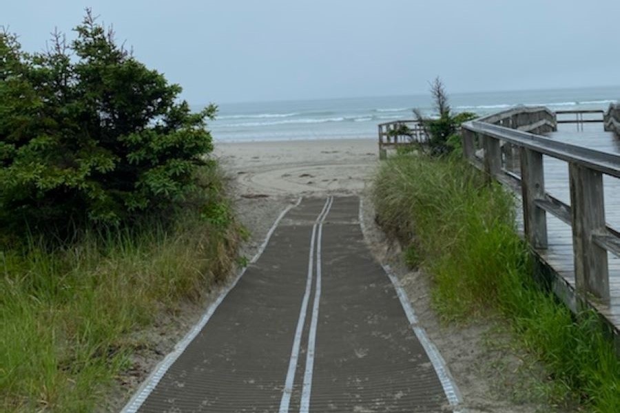 An adaptive beach mat next to a boardwalk.