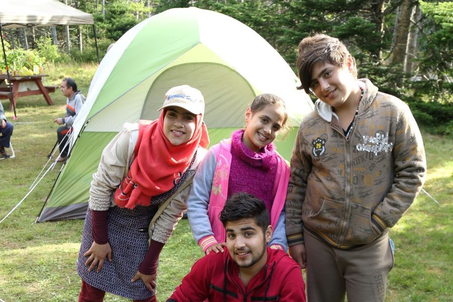 Four youth pose in front of a green tent. 