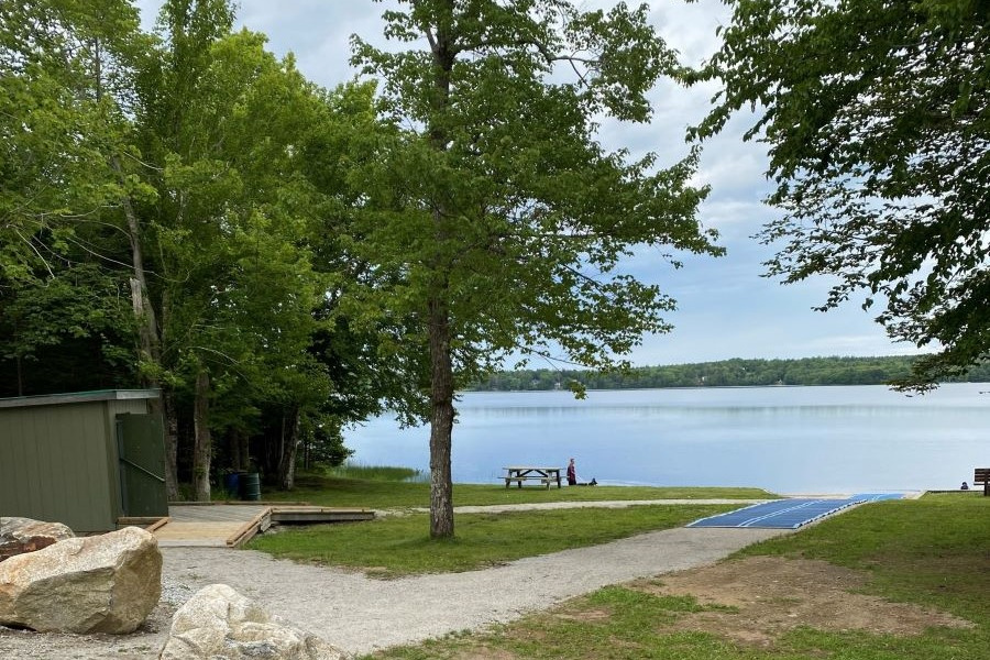 A gravel pathway leading to a mobi mat and lake front.